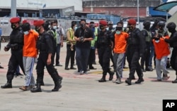 Polisi mengawal terduga militan saat tiba di Bandara Internasional Soekarno-Hatta, 18 Maret 2021. (Foto: AP)