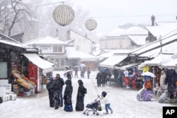 Turis berjalan di kawasan kota tua saat hujan salju lebat di pusat kota Sarajevo, Bosnia, Senin, 23 Desember 2024. (Armin Durgut/AP)