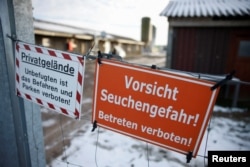 Tanda bertuliskan "Waspadai bahaya epidemi! Dilarang masuk tanpa izin!" tergantung di pagar depan sebuah peternakan di Mehrow, dekat Ahrensfelde, Jerman, 13 Januari 2025. (Axel Schmidt/REUTERS)